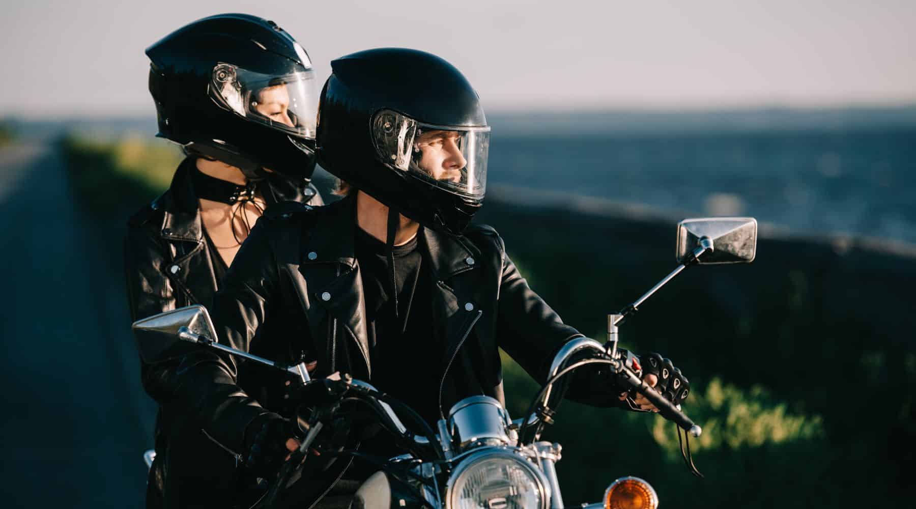 Man riding a motorcycle with woman on the back