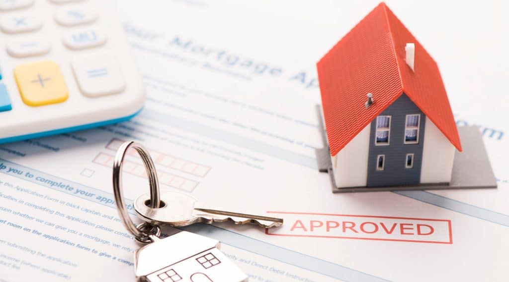 Model house and house keys on an aproved mortgage application form.