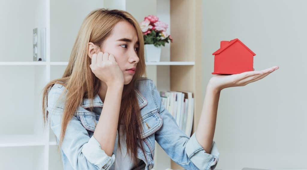 Stressed woman holding model of house