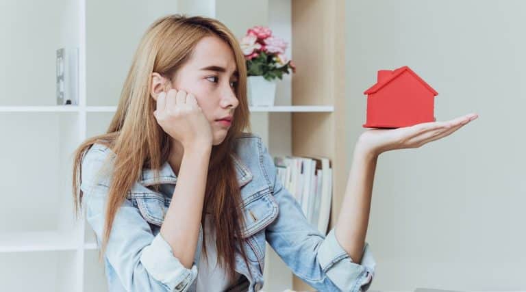 Stressed woman holding model of house