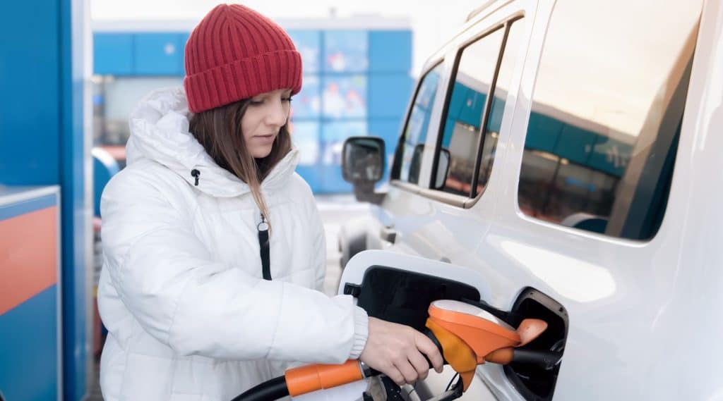 Woman in winter clothes filling her car with petrol