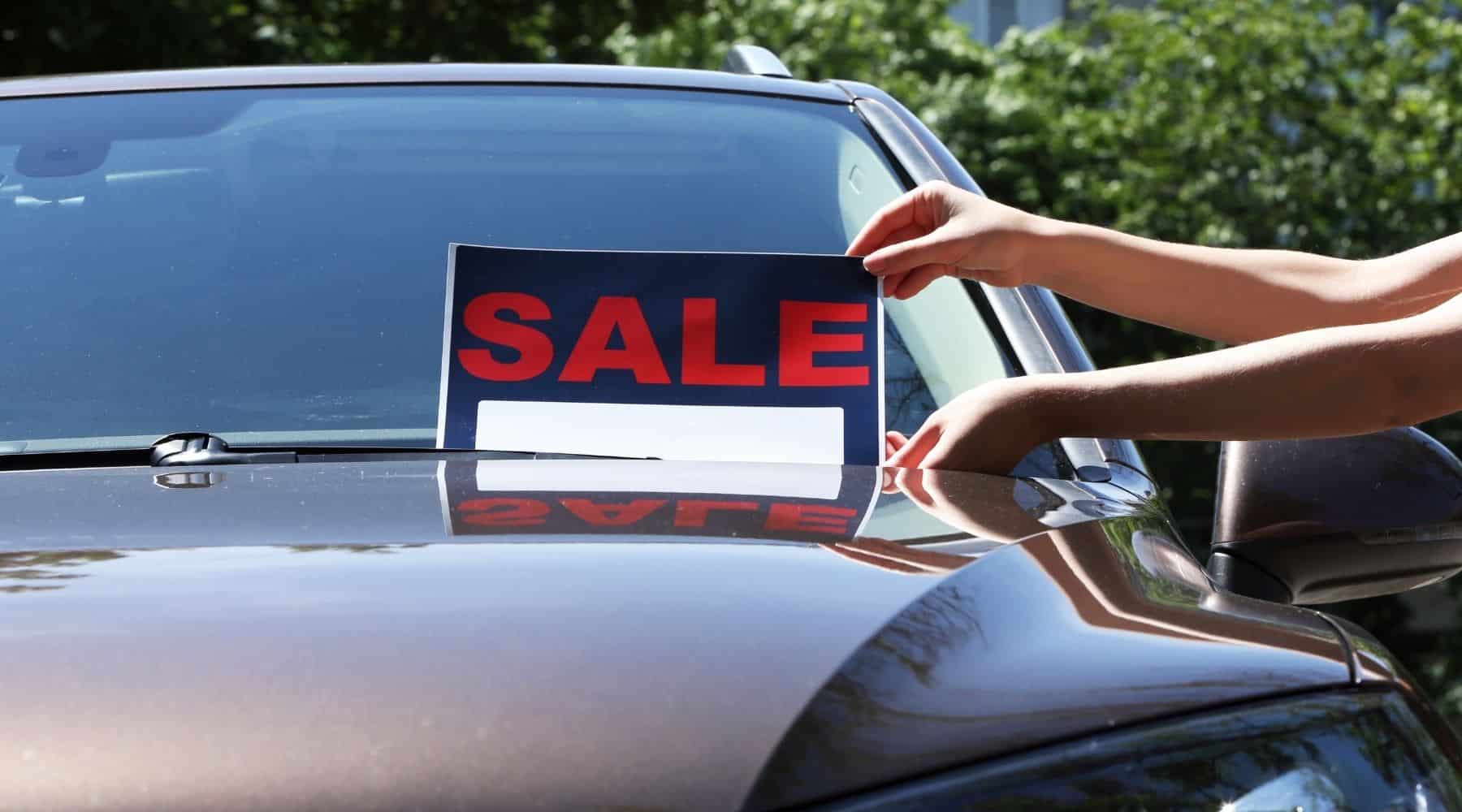 Sale sign being placed on car windshield