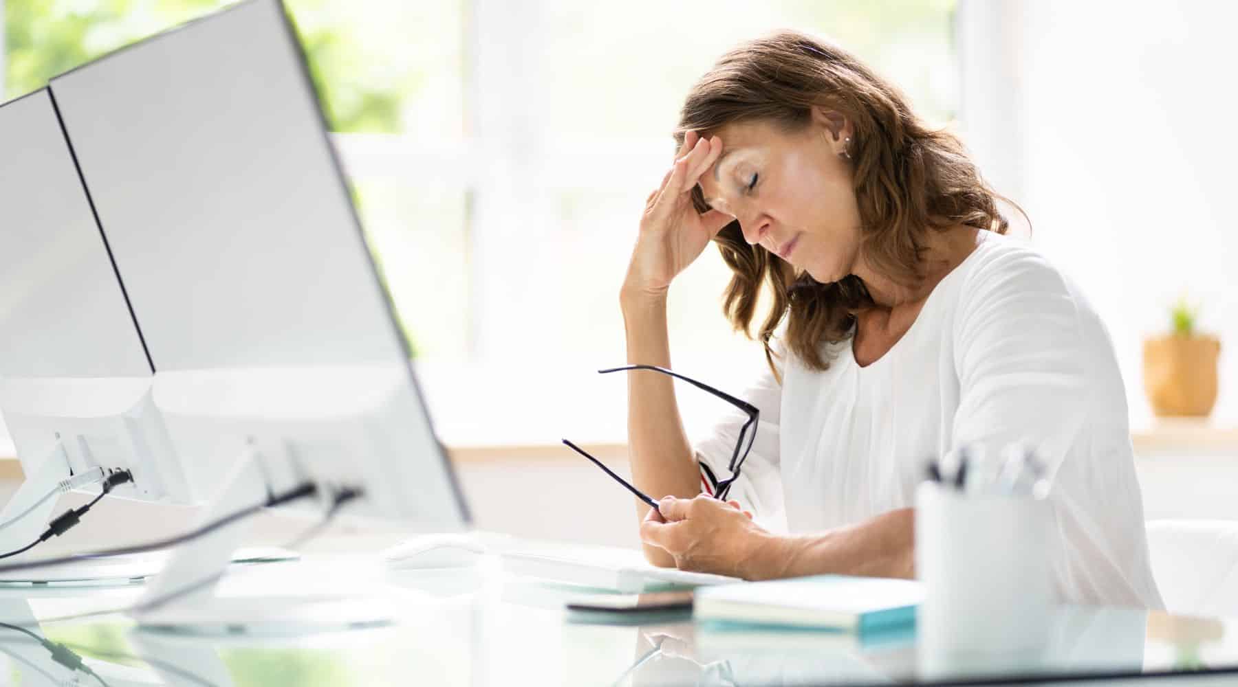 Woman holding her head while sitting at her computer