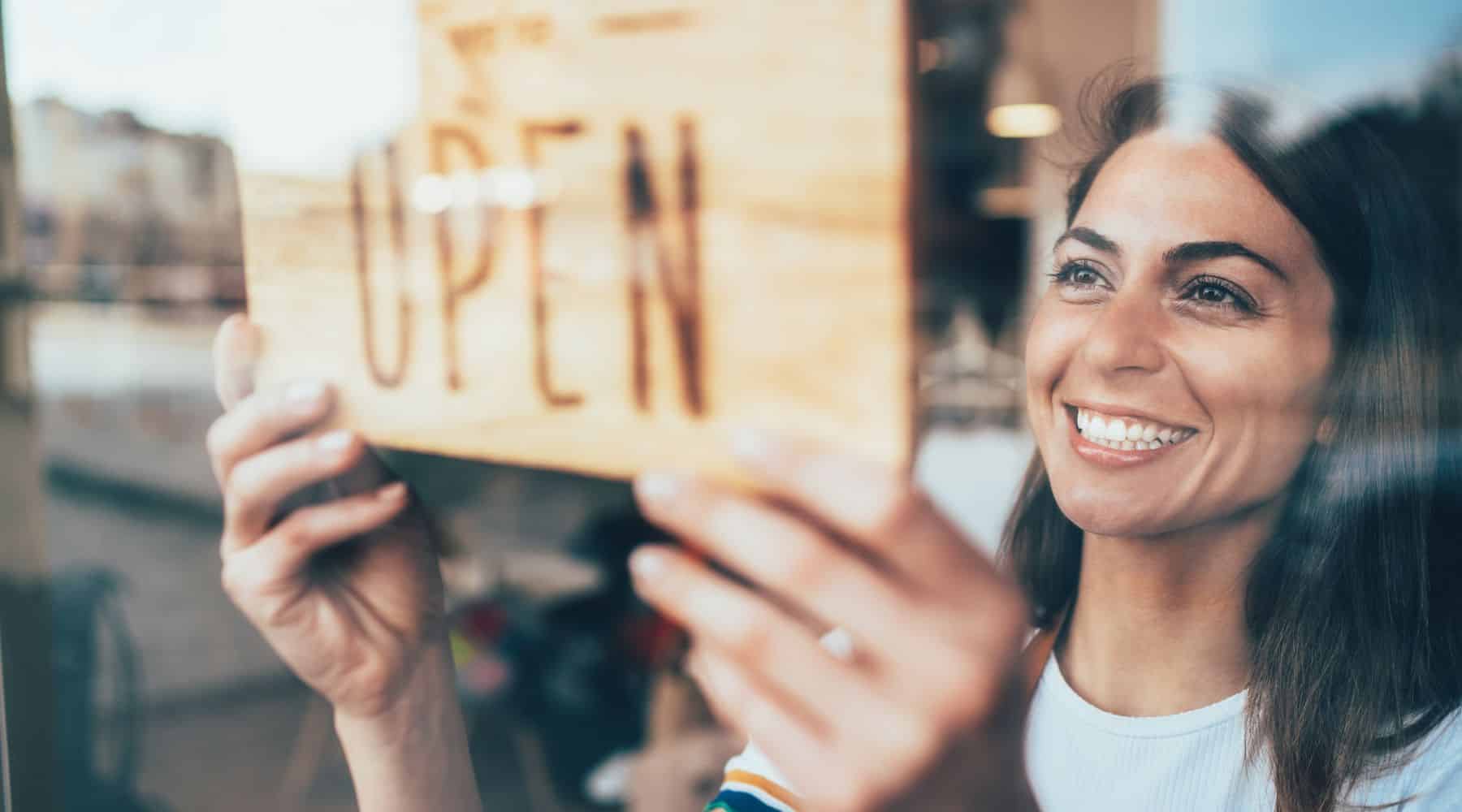 A woman outting open sign on business door