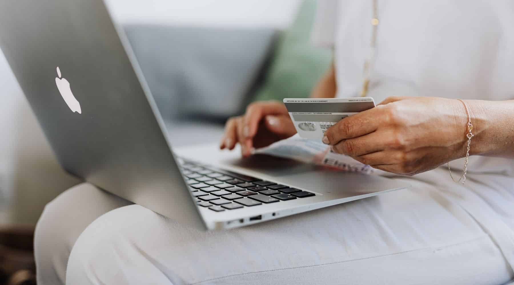 A person holding their credit card and using a laptop
