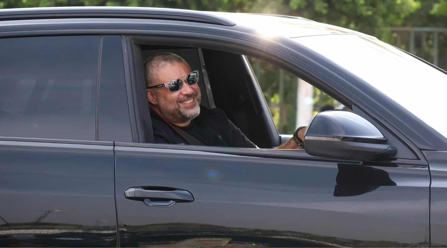Man smiling and wearing sunglasses while driving his car