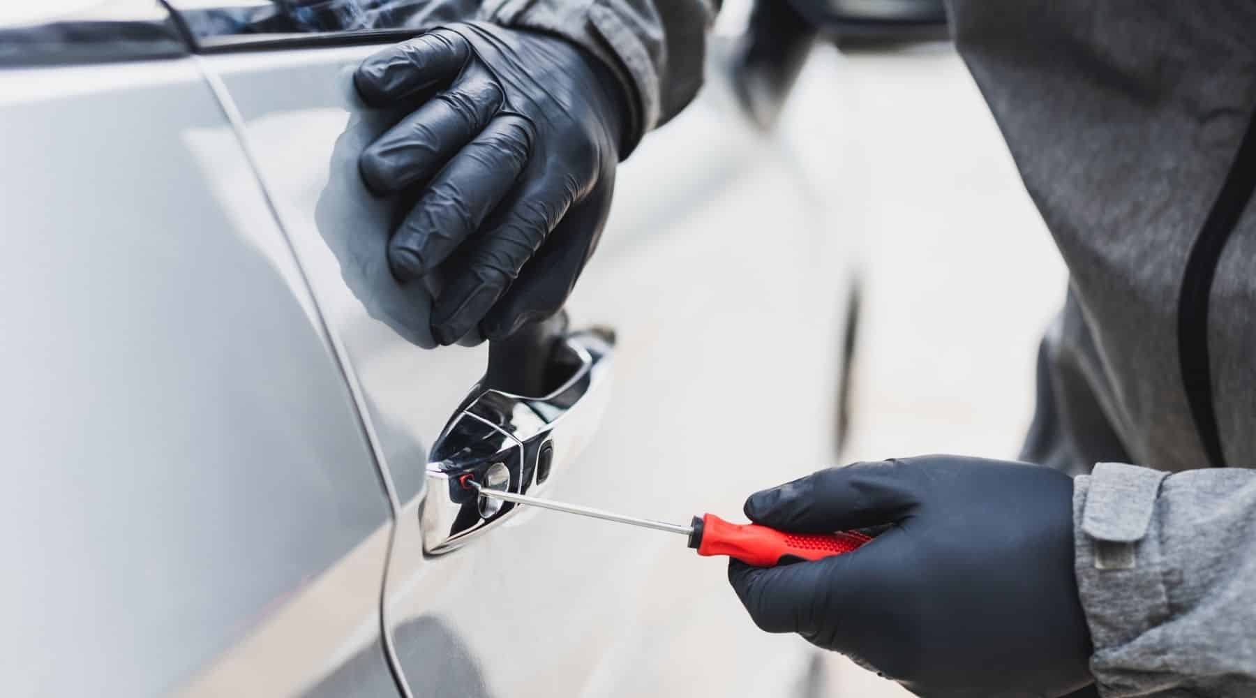 A person using a screwdriver to break into a car